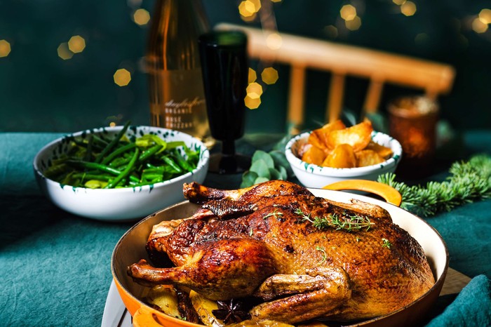 A roast duck main with side dishes in the background