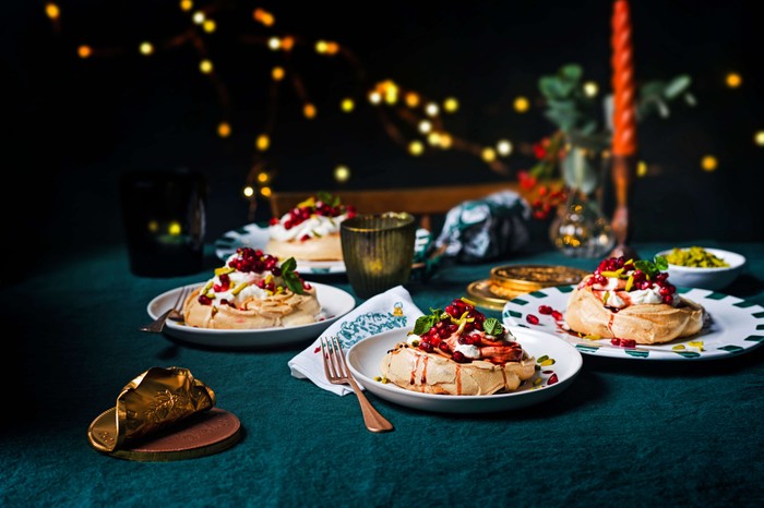 Several meringues on serving plates with a bright red sauce on top