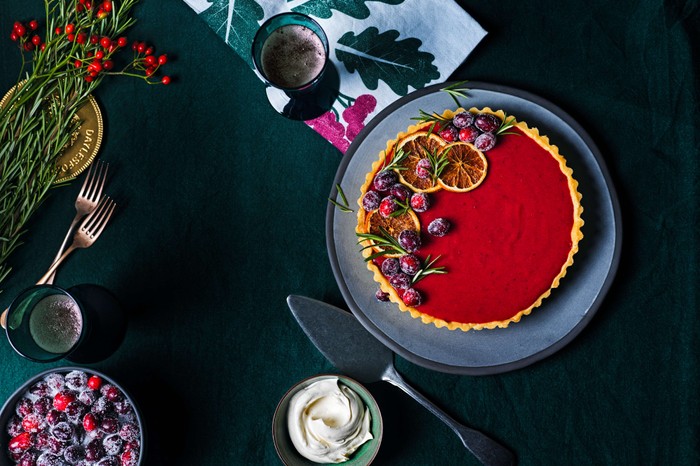 A bright red sweet tart with Christmassy paraphernalia in the background