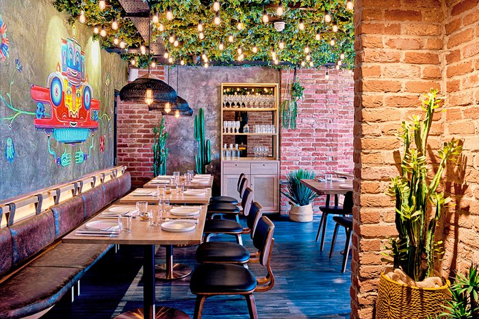 Interiors at Los Mochis, including a colourful mural, banquette and fairy lights and greenery on the ceiling