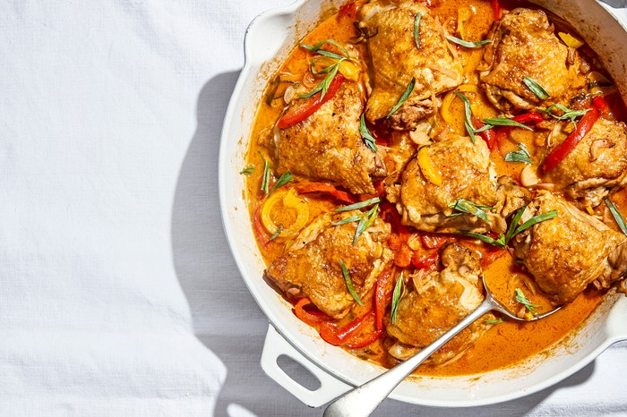 Chicken thighs in a tomato sauce in a white oven dish on a tablecloth