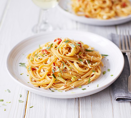 Two dishes of crab linguine topped with tarragon