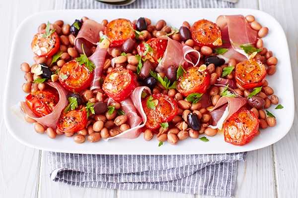 Tomato Salad Recipe with Prosciutto and Borlotti served on a long white late with a thin stripy blue and white cloth