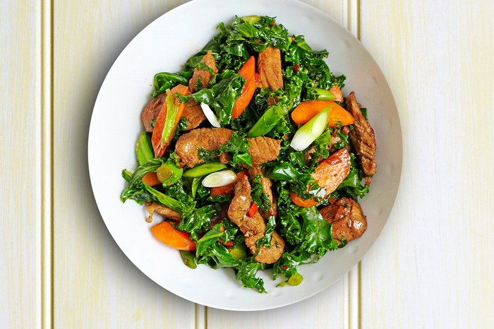 Stir-fried kale, pork and carrots with chilli in a white bowl