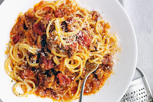 Spaghetti bolognese on a dish, topped with Parmesan