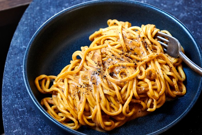 A big bowl of pasta with a fork tangled up in it