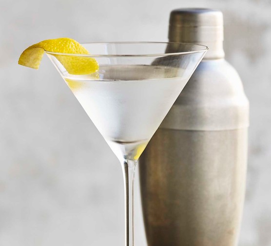 A martini cocktail next to a shaker