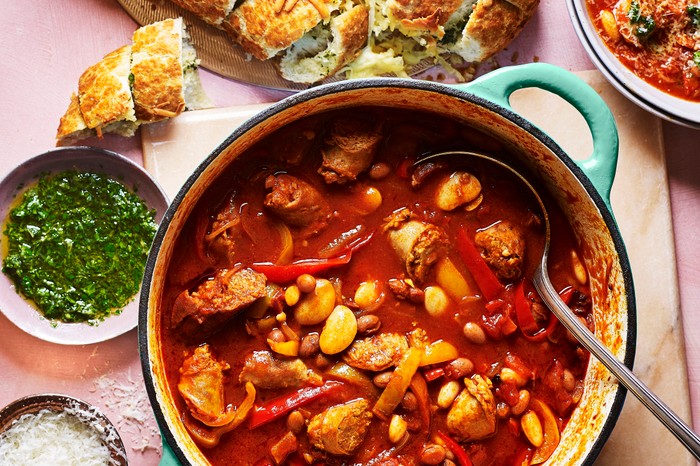 Sausage and bean casserole in a pot with garlic bread and gremolata on the side
