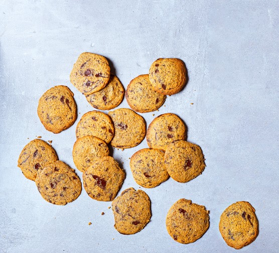 Sourdough rye choc chip cookies A light blue background topped with golden chocolate chip cookies