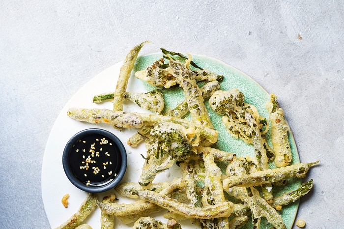 A white plate topped with fried broccoli in batter