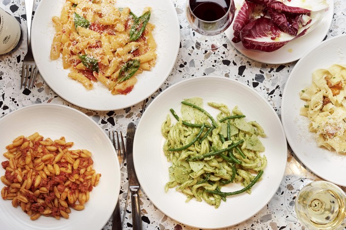 A marble table with lots of places of pasta on top