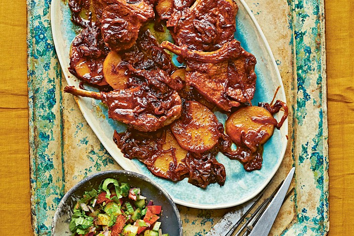 A blue rusted board topped with a platter of lamb chops covered in a ginger paste