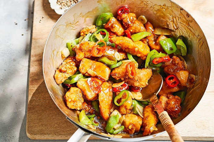 Silver pan of chicken and chillies on a rustic wooden board