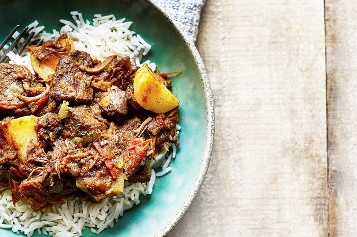 Bowl of goat curry with rice and a fork