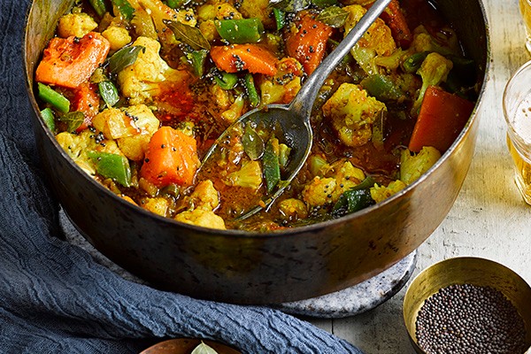 Pan of vegetarian curry with black pepper on the side