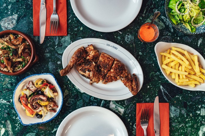 A table of Portuguese dishes including half a piri piri chicken at Casa do Frango