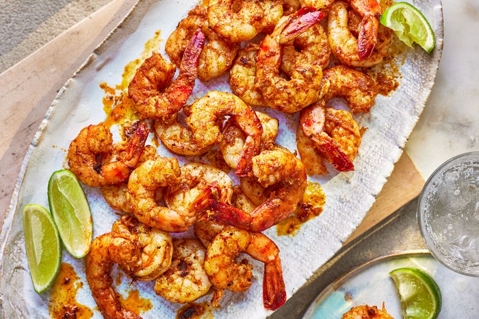 A platter of king prawns cooked in spices served with wedges of fresh lime