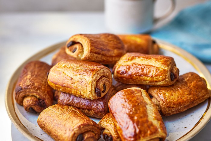 A plate of pain au chocolats with a mug of tea behind