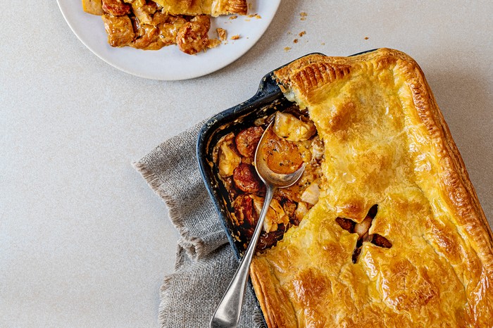 A black baking dish filled with a meat pie, topped with golden pastry