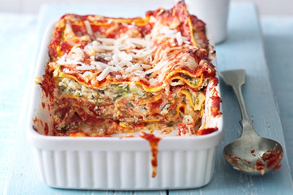 Courgette lasagne in a white rectangular baking dish with a spoon next to it