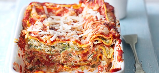 Courgette lasagne in a white rectangular baking dish with a spoon next to it