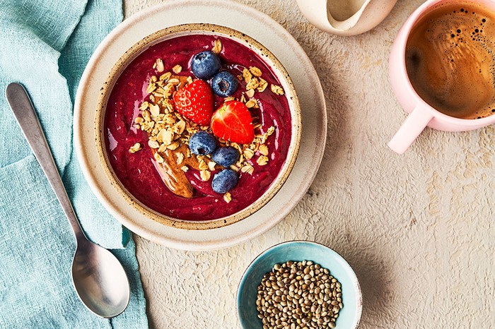 Smoothie bowl topped with strawberries, blueberries, oats and seeds