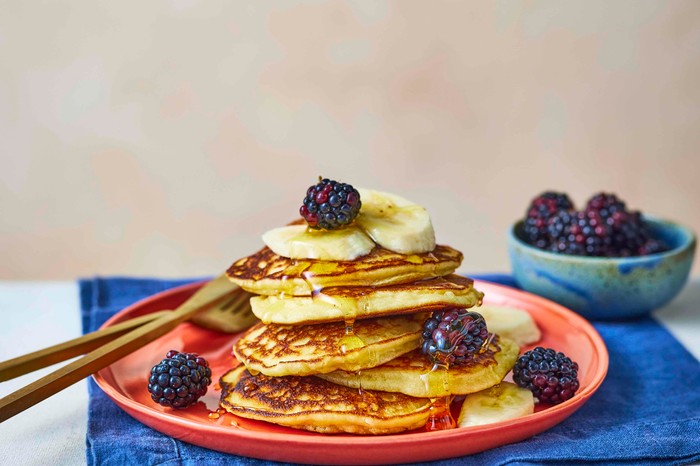 A stack of almond flour pancakes topped with blackberries, banana and honey