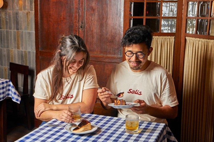 Solis owners Ana and Zijun sat at a table both tucking into a plate of cheesecake