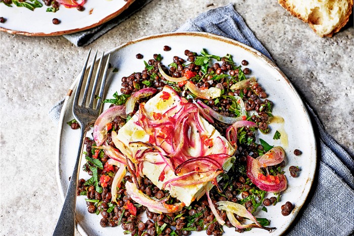 Lentil Salad Recipe with Feta and crunchy bread. Served on a white plate with a blue napkin on a grey table.