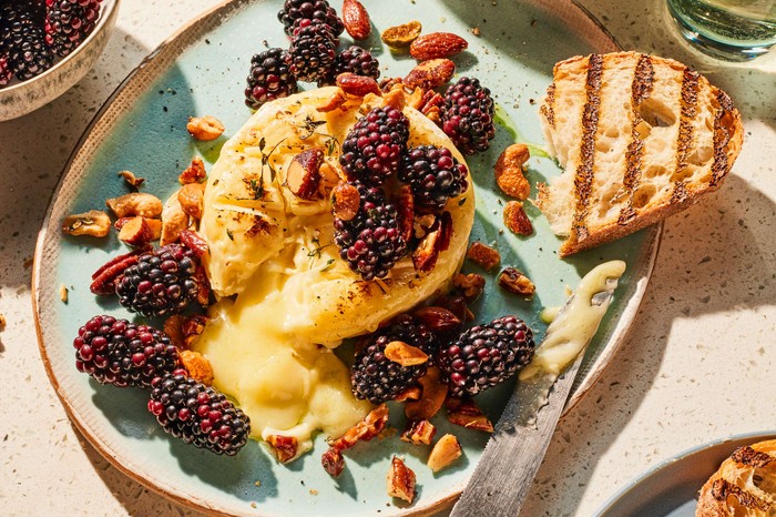 A melting baked brie with blackberries on the side