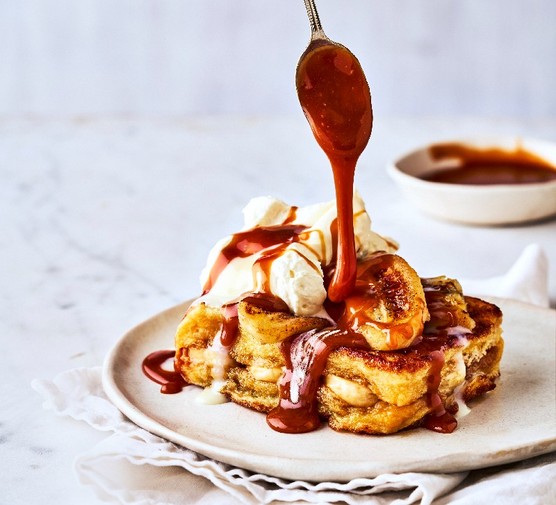 a plate of french toast with melted chocolate being poured from a spoon