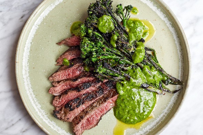 Bavette steak slices and served on a plate with greens