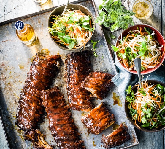 Three racks of ribs with three bowls of salad and a beer