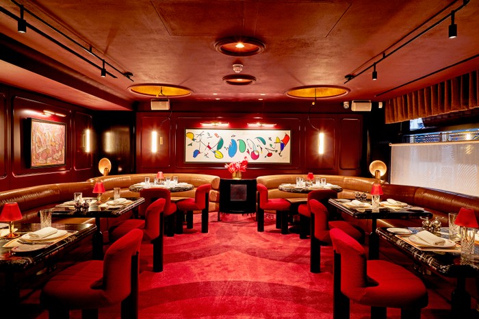 The interior at Bébé Bob, featuring bright red carpets, brown leather booths and modern art pieces