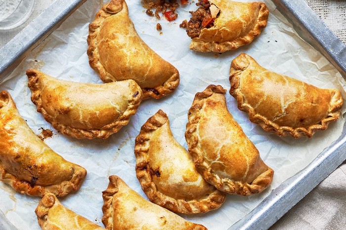 A silver baking tray filled with golden empanadas