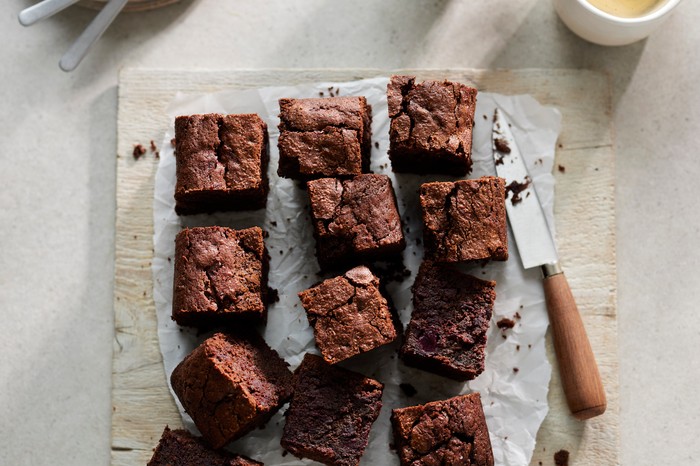 A slab of brownies cut into squares with a knife on the side