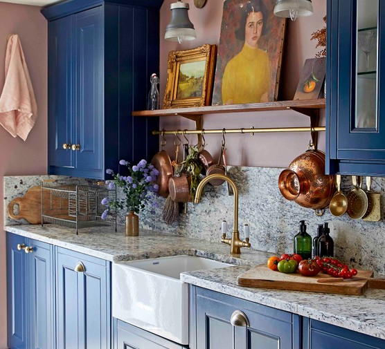 A kitchen with blue shaker-style units and a marble worktop