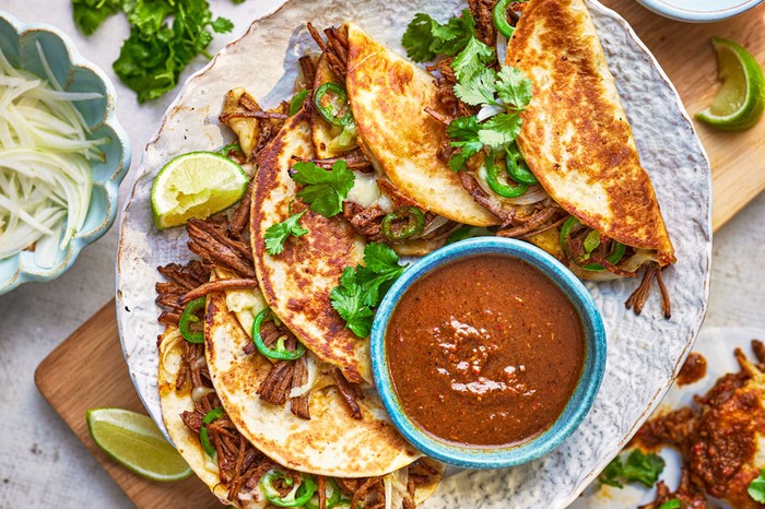 Beef tacos next to a bowl of gravy