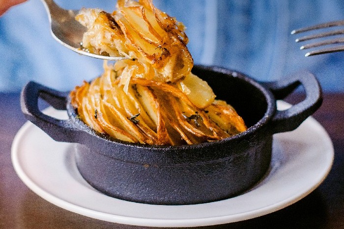 A small oven proof dish filled with Bottle + Rye’s braised lamb boulangère with a golden crisp top