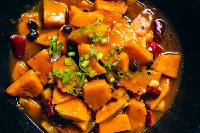 Bowl of squash and black beans topped with spring onion