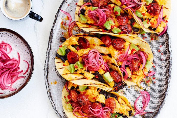 A tray of breakfast tacos holding scrambled egg, chorizo and beans