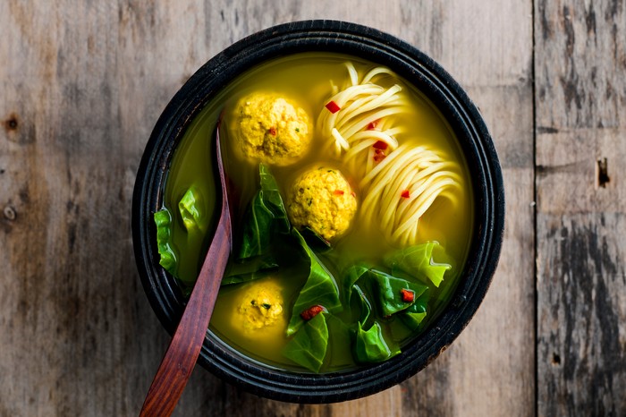 Turmeric Broth With Chicken And Ginger Dumplings. Bowl of turmeric broth with chicken and ginger dumplings