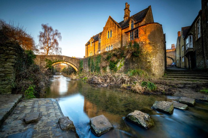 The Somerset town of Bruton on the river Brue Bruton, Somerset, England - February 7th, 2023. Bruton is a market town in the county of Somerset. Here, the river Brue which runs through the centre of the town can be crossed via a set of stepping stones.
