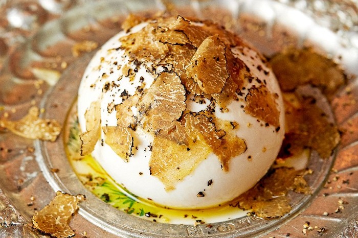 a silver plate of burrata covered in shavings of truffle