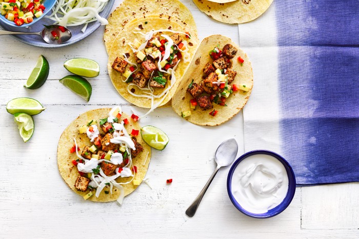 Cajun tofu tacos topped with salsa, cabbage, yogurt and lime wedges for squeezing over