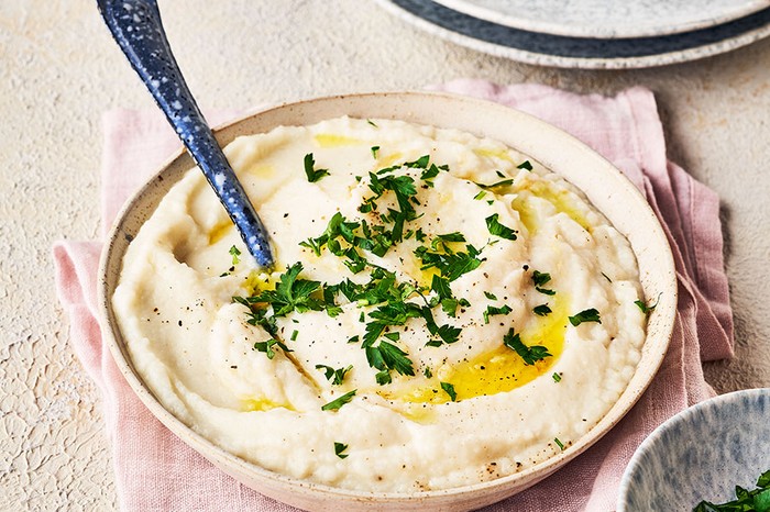 Bowl of cauliflower mash drizzled with olive oil and topped with parsley