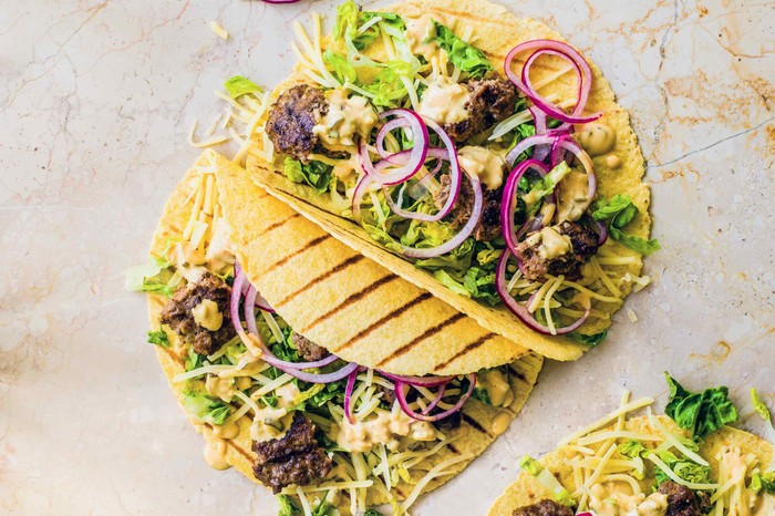 Cheeseburger Tacos Yellow tortilla wraps filled with mince, red onion and salad leaves