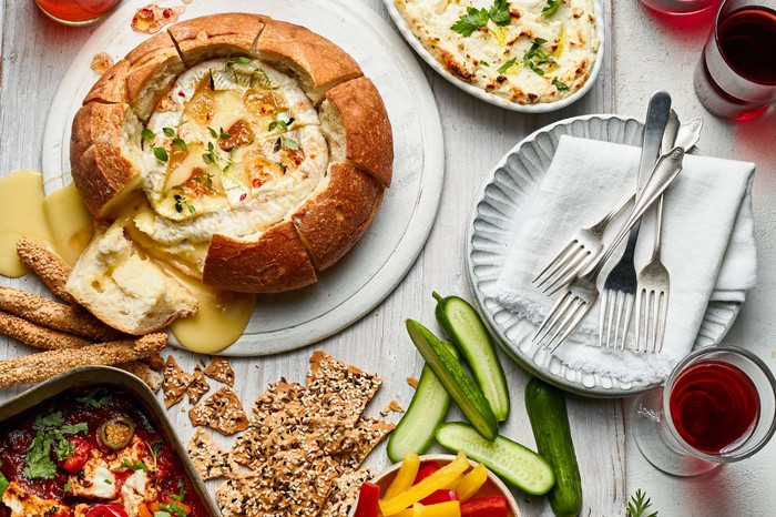 A spread of different baked cheeses with crudites on the side