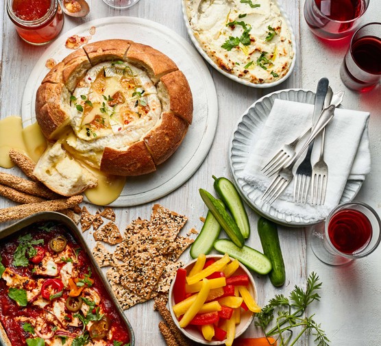 A spread of different baked cheeses with crudites on the side