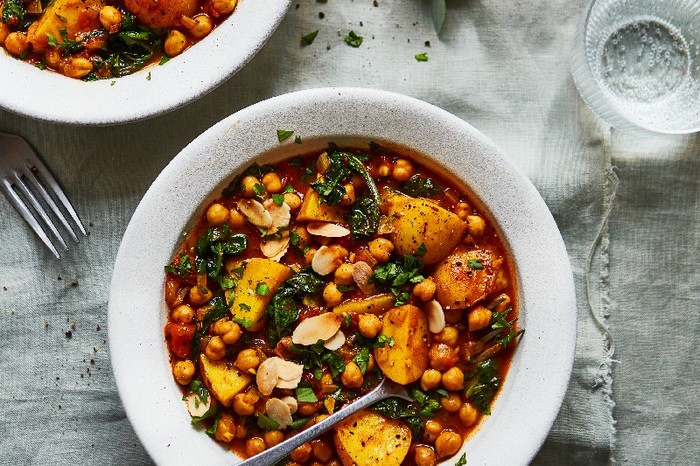 Two bowls of chickpea and potato tagine on a white linen table cloth